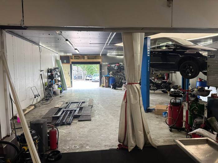 Korjaamohalli, jossa auto nostimella ja moottoripyöriä