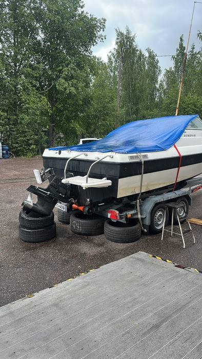 Vene trailerilla suojapeitteen alla korjaamon pihalla